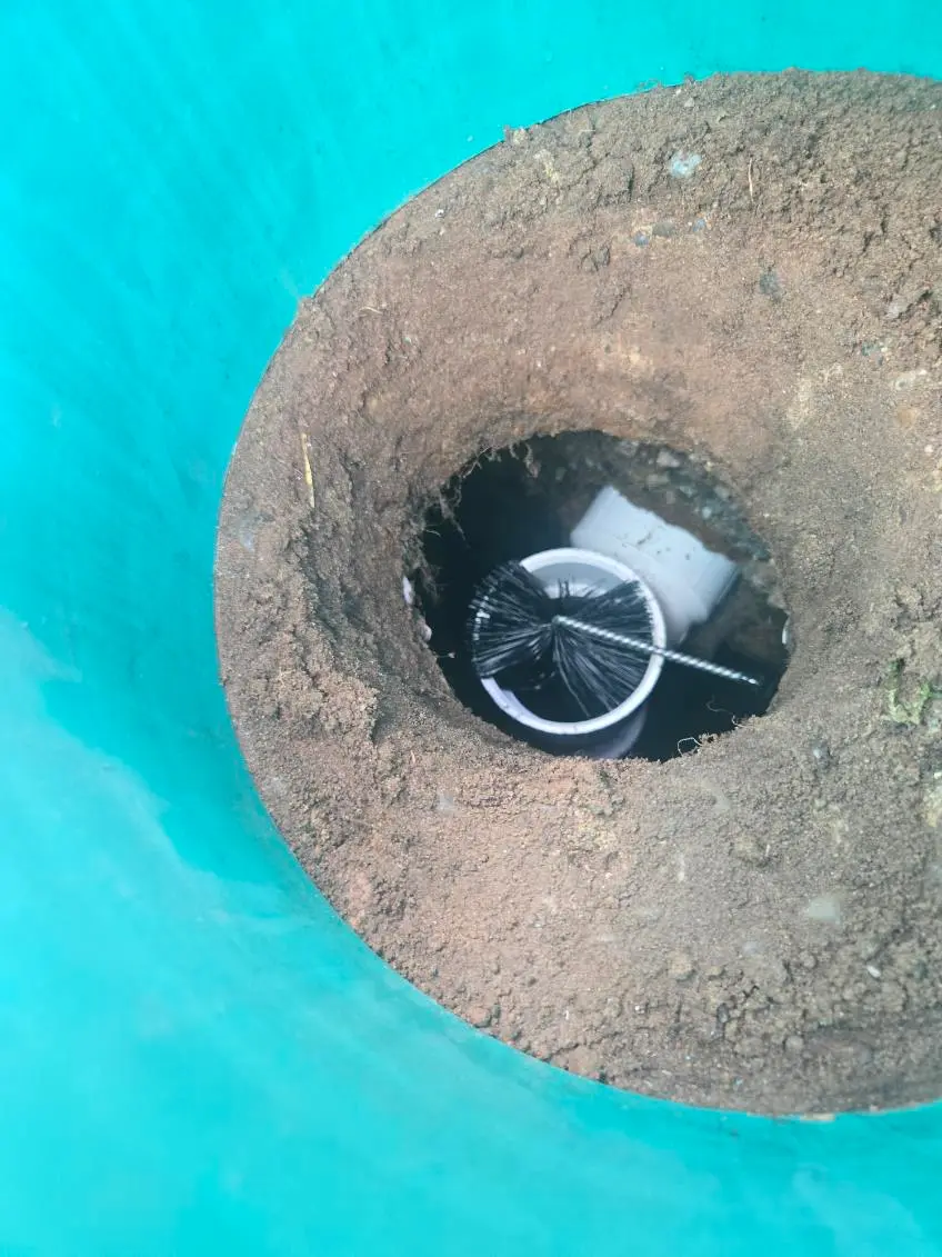 Septic Pros technician servicing the effluent filter in a septic tank's outlet baffle during a pump-out