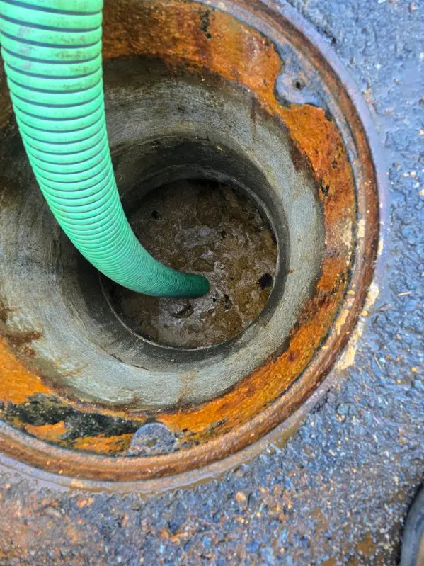 Septic Pros vacuum hose lowered into a tank access to pump it out